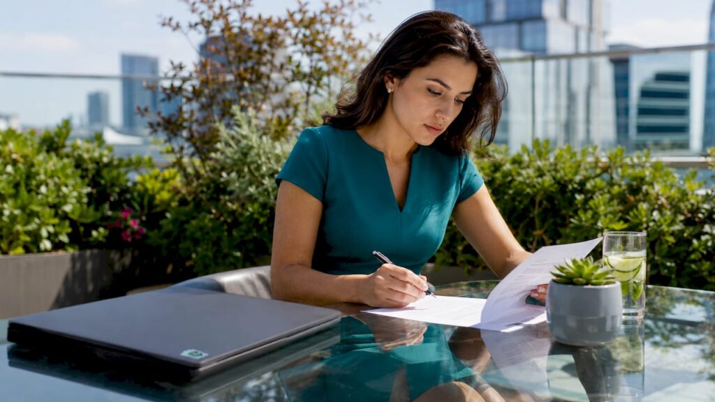 A woman reviewing and signing documents beside a laptop, illustrating consent paperwork and compliance checks for a legal content platform.